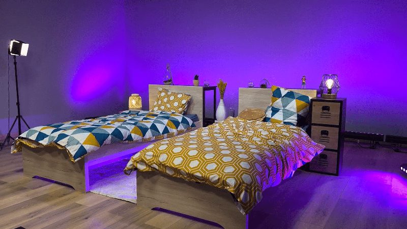 Décor chambre : deux lits et éclairage violet